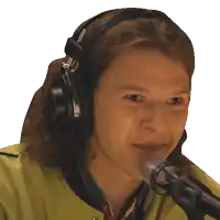 a woman wearing headphones and a yellow jacket is talking into a microphone