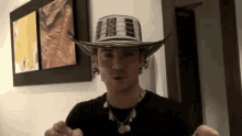a man wearing a hat and a necklace is standing in a room