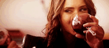 a woman is drinking a glass of wine and smiling .