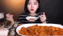 a woman is eating a large amount of food with chopsticks and a spoon .