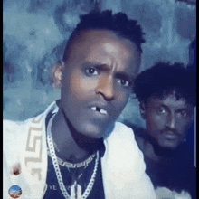 a man with a cigarette in his mouth is standing next to another man and making a funny face .