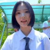 a girl wearing a white shirt and tie is smiling at the camera