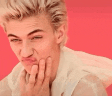 a close up of a man making a funny face with his hand on his chin .