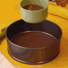 a person is pouring liquid into a cake pan that says mr.cakes on the bottom