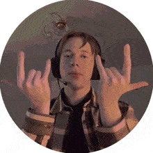 a man wearing headphones and a plaid shirt is making a horns sign