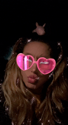 a woman wearing heart shaped sunglasses with a pink bunny on her head