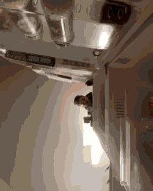 a man is looking out of a refrigerator door with a bottle of coca cola in it
