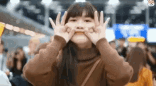 a girl is making a funny face with her hands .