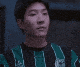 a young man wearing a green and black striped shirt with the word united on it