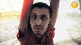 a man in a red shirt is hanging upside down with his arms in the air