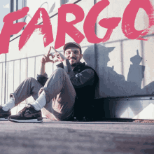 a man sits on the ground in front of a wall with the word fargo above him