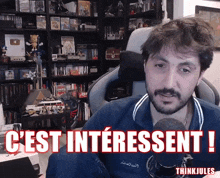 a man sitting in front of a microphone with the words " c'est interessant " on the bottom