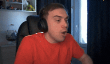 a man wearing headphones and a red shirt is sitting in front of a window