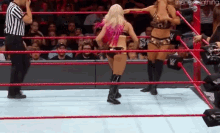two women are wrestling in a wrestling ring with a referee watching .