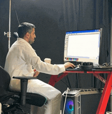 a man in a lab coat sits at a desk with a computer screen that says adobe illustrator