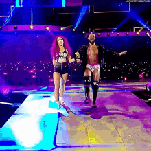 a man and a woman are walking down a stage with their arms outstretched