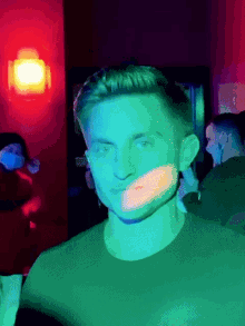 a man is standing in a dark room with a green light behind him