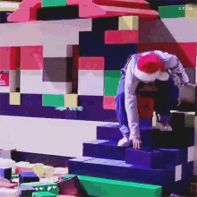 a person wearing a santa hat climbs a set of stairs made of lego blocks