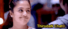 a girl is smiling in front of a banner that says thirudan chat