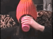 a person wearing a pink hat is holding a pink cup in front of their face