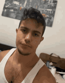 a young man in a white tank top is taking a selfie