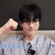 a man wearing glasses and a striped shirt has a fist up in front of his ear