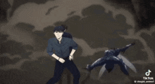 a man in a black shirt is standing next to another man in a black shirt who is laying on the ground .