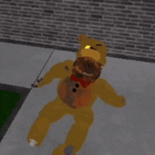 a yellow teddy bear is laying on a sidewalk in front of a brick wall .