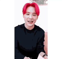 a young man with red hair is wearing a black shirt and looking at the camera