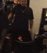 a man in a black shirt is standing in front of a computer monitor .