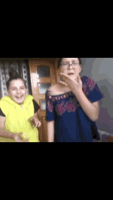 two girls are standing next to each other and one is wearing glasses and a yellow vest
