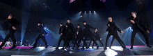 a group of men are dancing on a stage in a dark room .