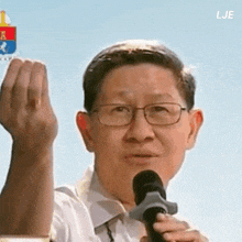 a man wearing glasses is holding a microphone and talking