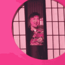 a man is standing in a pink circle in front of a pink wall .