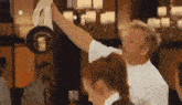 a man is holding a pan over his head while a woman watches .