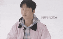 a young man wearing a pink jacket and a plaid shirt is talking in a foreign language .