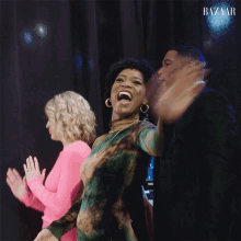 a woman in a pink dress stands next to a man in a black suit and another woman in a green dress