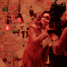 a woman is looking through a magnifying glass while a man holds a camera behind her