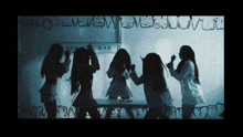 a group of girls are standing in front of a white board with letters written on it including the letters m and j