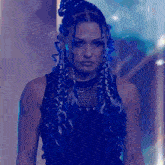 a woman with blue braids is wearing a black top and a black tank top .