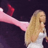 a woman with long blonde hair is singing into a microphone