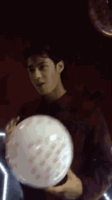 a man in a red shirt is holding a white balloon