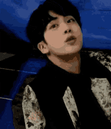 a young man is making a funny face while laying on a blue couch .