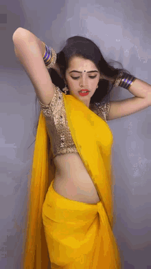 a woman wearing a yellow saree and gold blouse