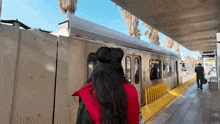 a woman in a mickey mouse hat walks towards a train