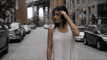 a woman in a white tank top walking down a street