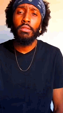 a man with a beard wearing a bandana and a black shirt .
