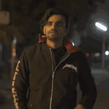 a man wearing a black jacket that says " supreme " on the sleeves