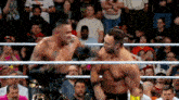 two men are fighting in a wrestling ring with a crowd watching .