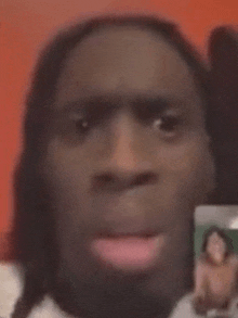 a man with long hair is holding a picture of a woman in front of his face .